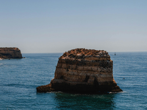 Stunning rock formation in the Algarve's deep blue waters under a clear sky.